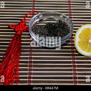 saucer with leaves of tea and the cut lemon on a rug Stock Photo