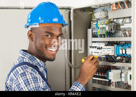 Technician Checking Fusebox With Screwdriver Stock Photo
