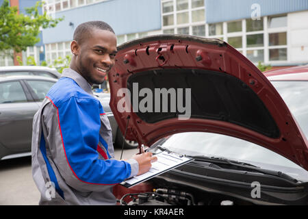 Mechanic With Clipboard In Front Of A Car Stock Photo