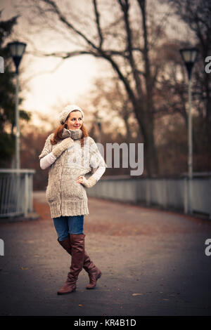 Autumn/winter portrait: young woman dressed in a warm woolen cardigan posing outside in a city park Stock Photo