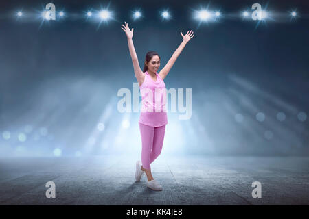 Excited asian runner woman after exercising with spotlight background Stock Photo