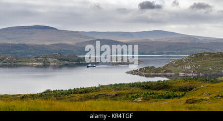 A fishing boat passes between rocky islands and peninsulas in Loch Torridon, an inlet of the Atlantic Ocean on the west coast of the Highlands of Scot Stock Photo