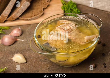 fish soup with sturgeon, potatoes in transparent plate, decorated garlic, parsley leaves, and cutted rye bread, healthy lifestyle Stock Photo