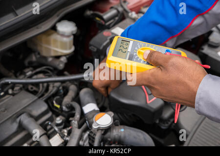 Mechanic Checking Battery With Multimeter Stock Photo