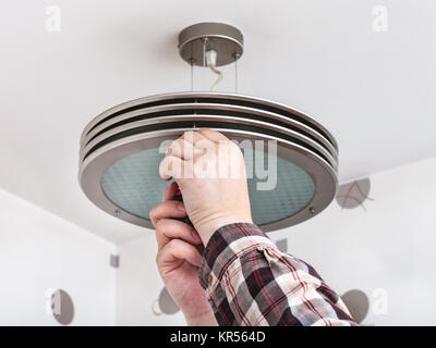 Electrician fixes round ceiling light Stock Photo