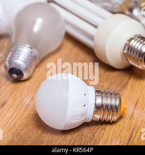 one new LED lamp and pile of used bulbs on board Stock Photo