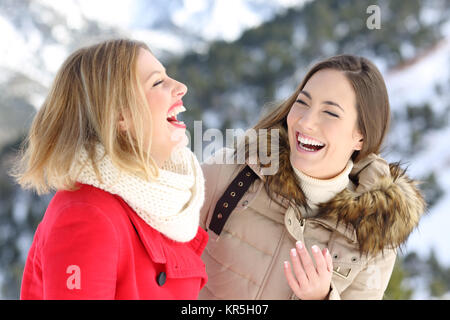 Two happy friends laughing loud enjoying winter holidays in a snowy mountain Stock Photo