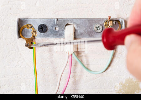 Electrician repairs wiring in wall light Stock Photo