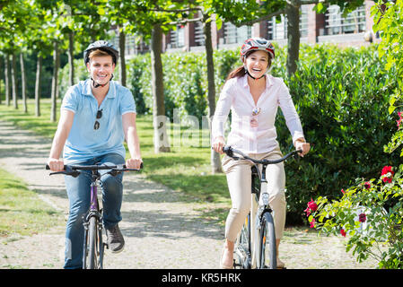 Smiling Couple Riding On Bicycles In The Park Stock Photo
