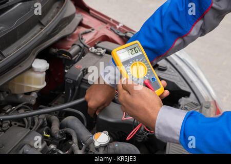 Mechanic Checking Battery With Multimeter Stock Photo