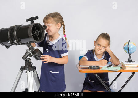 Girl astronomer looks through the eyepiece of the telescope, the other girl thinking waiting for the results of observations Stock Photo