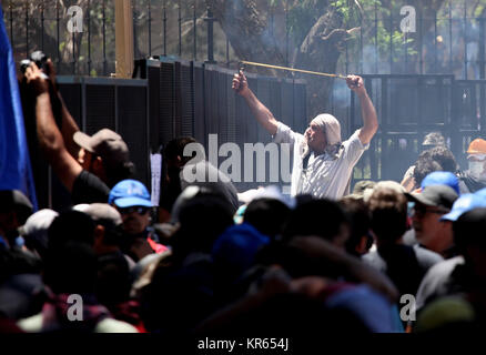 Buenos Aires, Argentina. 18th Dec, 2017. A protester fires stones at the police forces with a sling in front of the Chamber of Deputies of the National Congress in Buenos Aires, Argentina, 18 December 2017. Heavy clashes occurred between protesters and police forces whilst a parliamentary debate on a planned pension reform. Credit: Claudio Santisteban/dpa/Alamy Live News