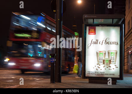 London, England, UK - October 11, 2010: A traditional red double-decker London bus pulls away from a bus stop on Westminster Bridge at night, with the Stock Photo