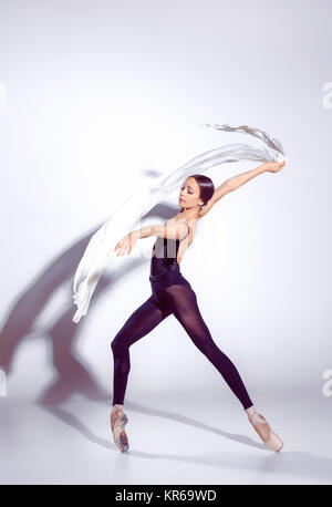 Ballerina in black outfit posing on toes, studio background. Stock Photo