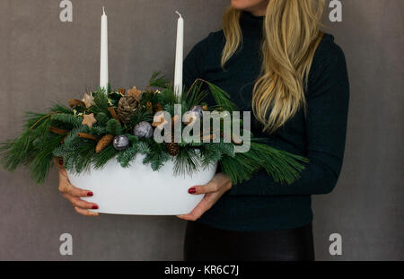 Beautiful woman holding Christmas fir composition with candles in the white pot Stock Photo