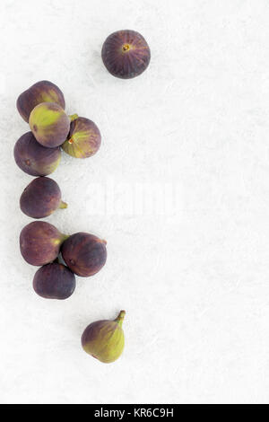 Whole fresh figs arranged on a white marbled background with lots of copy space. Top view. Stock Photo