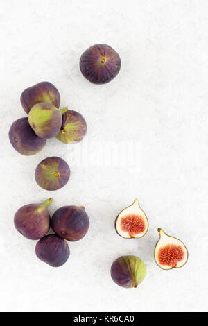 Arrangement of fresh whole and cut figs and on a white marbled background with lots of copy space. Top view. Stock Photo