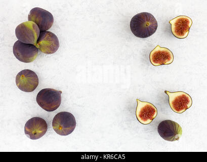 Arrangement of whole and halved figs on a white marbled background with copy space. Top view. Stock Photo