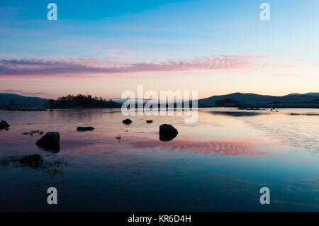 The sun rises over a wintry scene at Loch Ba on Rannoch Moor in the Highlands of Scotland Stock Photo