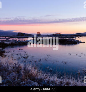 The sun rises over a wintry scene at Loch Ba on Rannoch Moor in the Highlands of Scotland