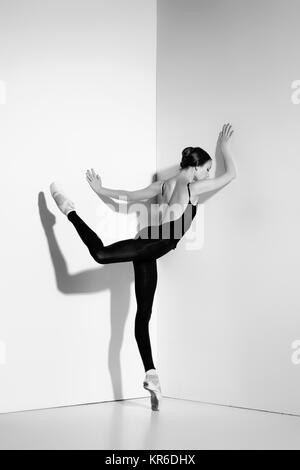 Ballerina in black outfit posing on pointe shoes, studio background. Stock Photo