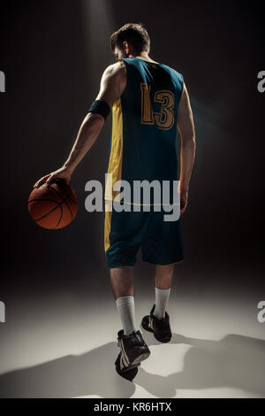 Silhouette view of a basketball player holding basket ball on black background Stock Photo