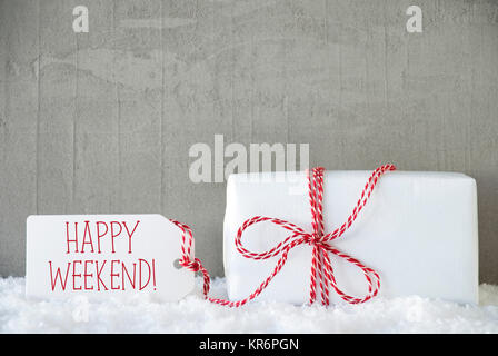 One Christmas Gift Or Present On Snow With Red Ribbon. Cement Or Concrete Wall As Background. Modern And Urban Style. Card For Birthday Or Seasons Greetings. Label With English Text Happy Weekend Stock Photo