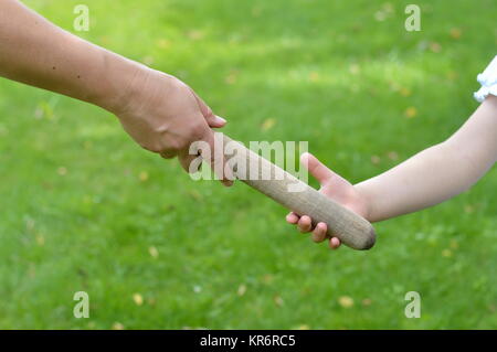woman giving the relay baton to the next generation into a child's hand Stock Photo