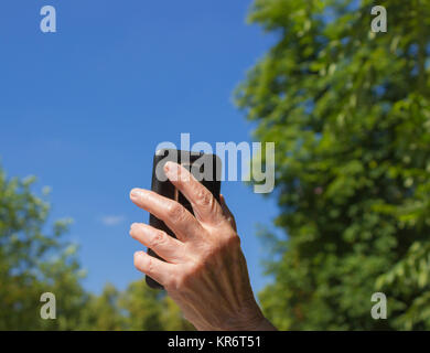 The phone in hand of old woman on the blue sky background Stock Photo