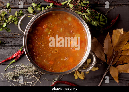 high-angle shot of a stainless steel with a lentil stew on a gray rustic wooden table Stock Photo