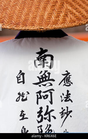 Rear view of Buddhist nun wearing traditional clothing and straw hat. Stock Photo