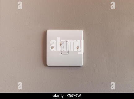 UK domestic single light switch in white plastic on a buscuit coloured wall Stock Photo
