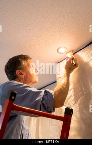 Senior adult man painting ceiling of kitchen Stock Photo