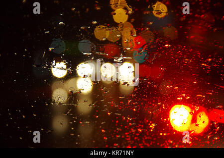Raindrops on car window. City lights blurred by water drops on glass. Stock Photo