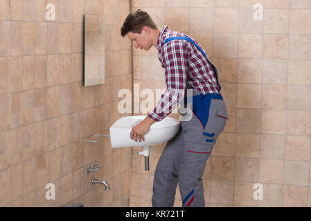 Male Plumber Installing Sink In Bathroom Stock Photo