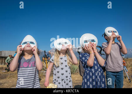 Group of children look up wearing eclipse glasses to watch Solar Eclipse, Grand Tetons National Park, Teton County, Wyoming Stock Photo