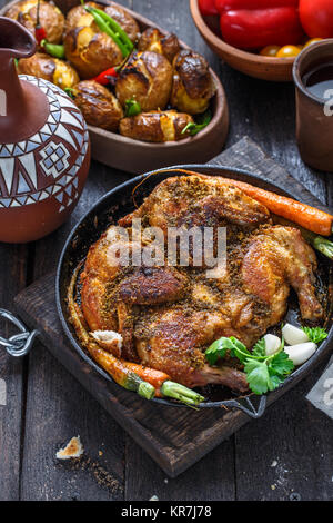 Whole roast chicken in an iron pan on dark background Stock Photo