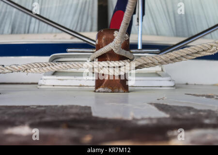 Multiple ropes tied to wooden cleat on vintage wooden boat Stock Photo