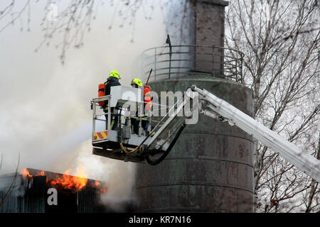 SALO, FINLAND - FEBRUARY 16, 2014: Firefighters extinguishing flames on a hydraulic crane platform at the Salo Cement Plant, which breaks out in fire  Stock Photo