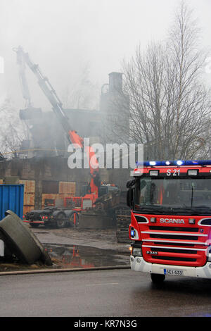 SALO, FINLAND - FEBRUARY 16, 2014: Firefightes extinguish the smouldering fire at Salo Cement Plant with the help of a mobile crane. Stock Photo