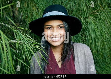 Portrait of smiling mixed race woman near foliage Stock Photo