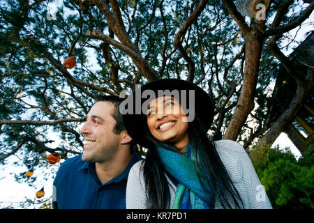 Couple smiling under lanterns hanging in tree Stock Photo