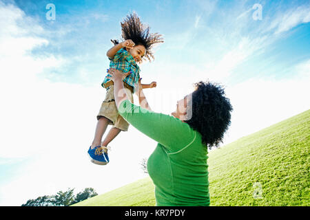 Smiling mixed race lifting son outdoors Stock Photo