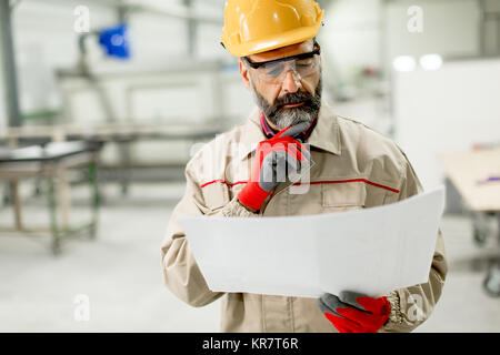 Handsome mature engineer looking at plan in the factory Stock Photo