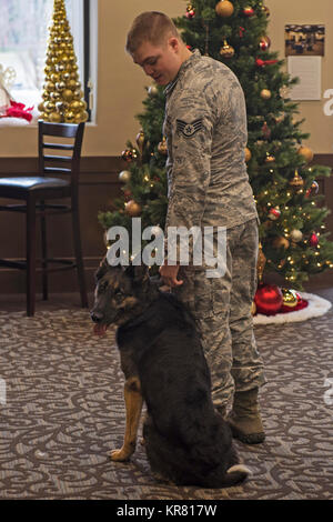 Military Working Dog Oxigen sits beside Staff Sgt. Thomas Newman, 92nd Security Forces Squadron MWD handler, following her retirement ceremony Nov. 30, 2017, at Fairchild Air Force Base, Washington. Newman was Oxigen’s third and final handler during her last two years of service. (U.S. Air Force Stock Photo