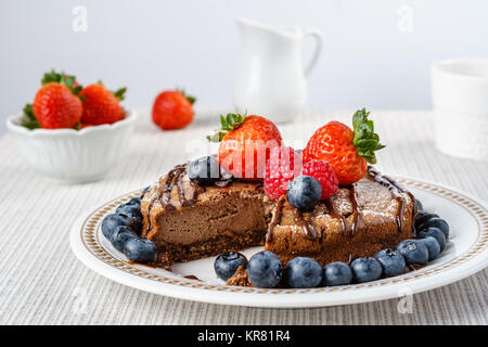 Big chocolate cheesecake with blueberry strawberry raspberry on a round plate. Stock Photo
