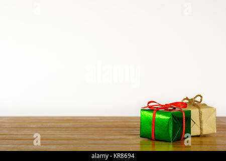 Metallic green and brown paper gift packages on a wooden table against a white background. Stock Photo