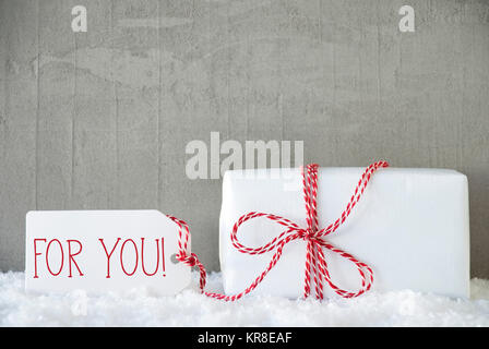 One Christmas Gift Or Present On Snow With Red Ribbon. Cement Or Concrete Wall As Background. Modern And Urban Style. Card For Birthday Or Seasons Greetings. Label With English Text For You Stock Photo