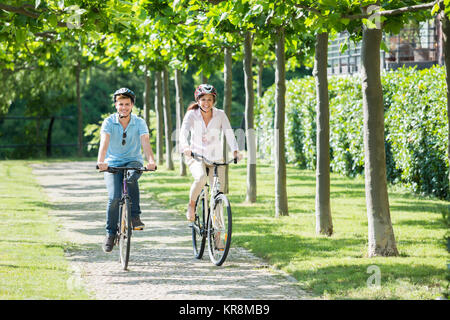Smiling Couple Riding On Bicycles In The Park Stock Photo