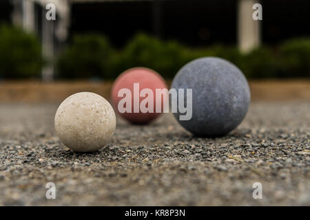 Bocce Balls on Gravel White in Focus with Red and Blue in Background Stock Photo